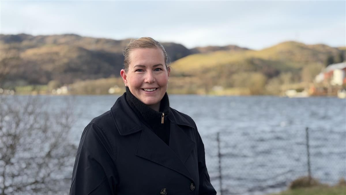 Dame som står foran et vann - Klikk for stort bilde